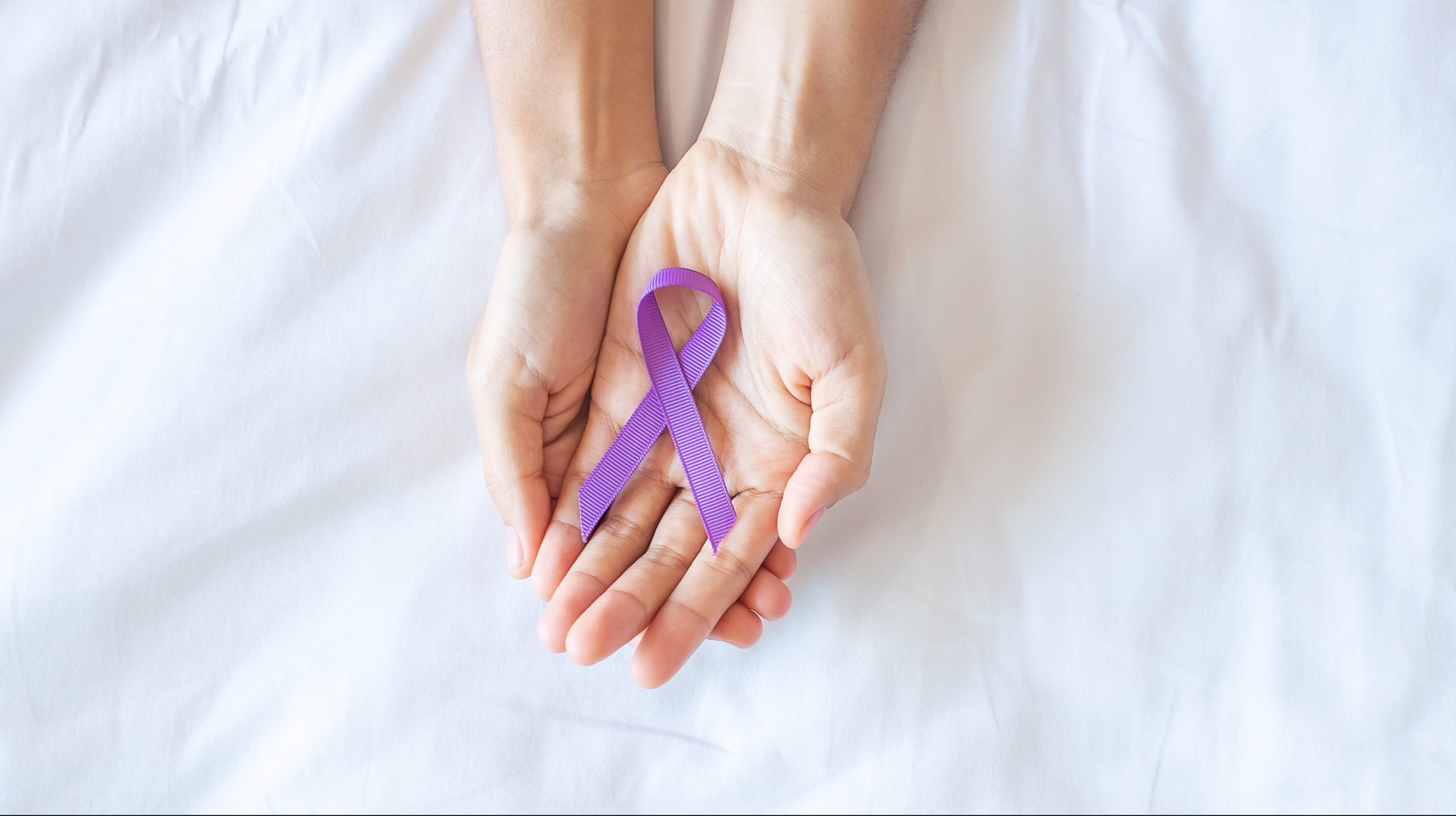 hand holding purple Ribbon. Pancreatic Cancer, epilepsy, lupus and domestic violence day Concept